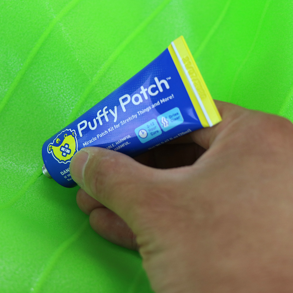 Hand holding Puffy Patch adhesive tube